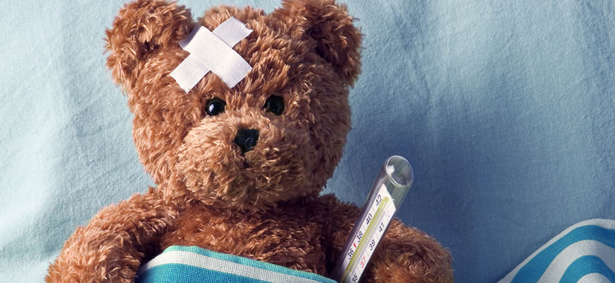 Image of a teddy bear on a bed with a plaster on there head